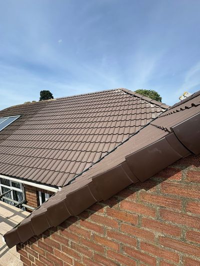 Finished brown interlocking tiled roof with new ridge tiles running down the verge