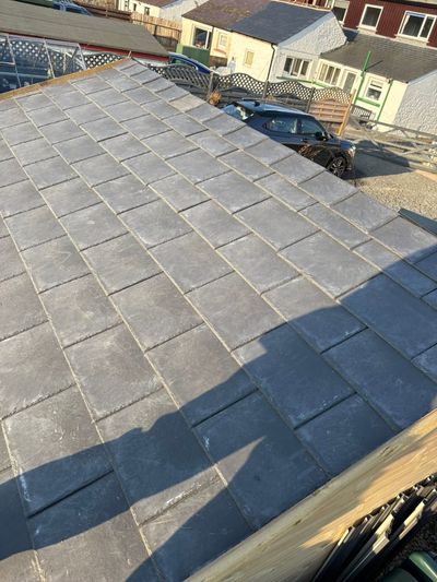 Newly laid composite slate roof seen down the slope towards neighbouring houses